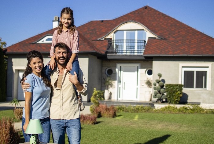 Smiling couple outside home with child